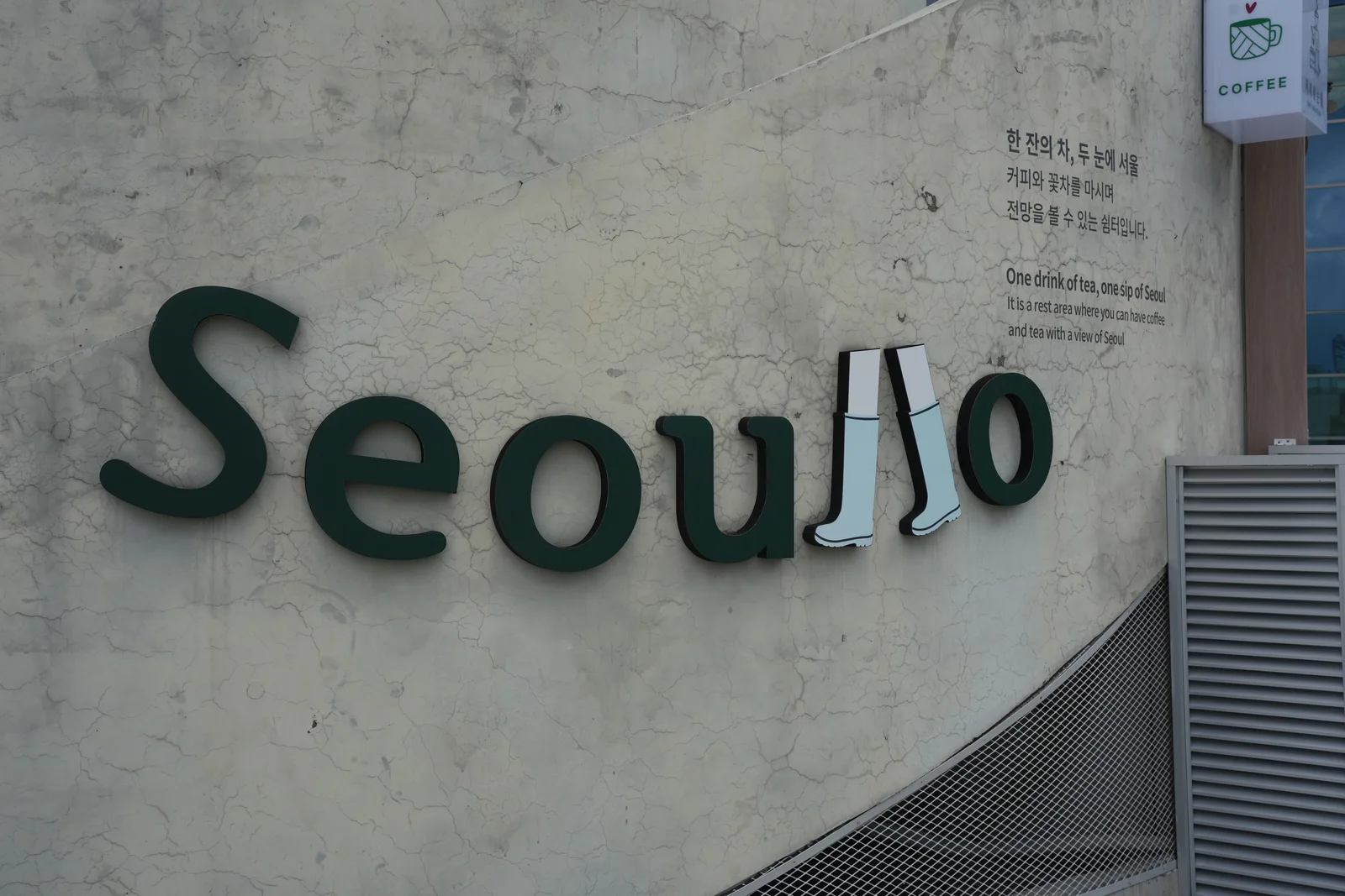 The Seoullo wordmark mounted on a weathered concrete wall, with the double-L rendered as a pair of white rain boots.