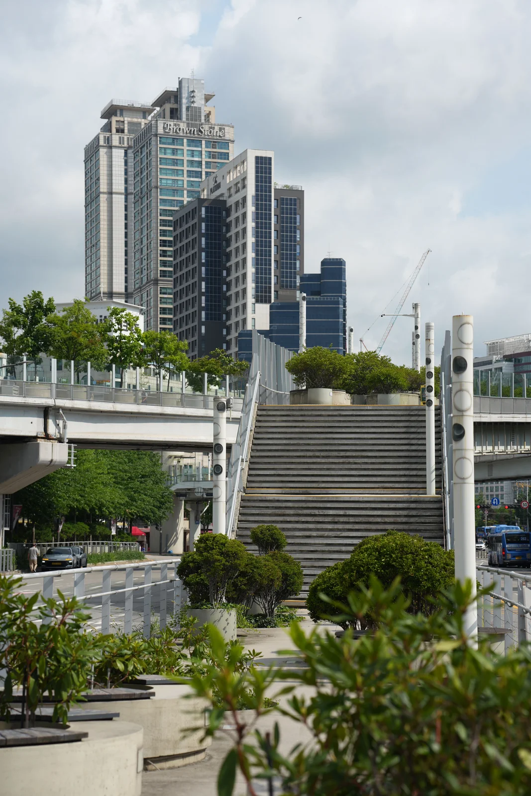The elevated Seoullo walkway lined with circular concrete planters and small trees, with high-rise towers behind.